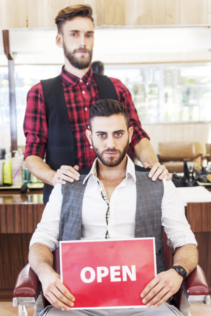 young hipster couple posing in their vintage barber shop